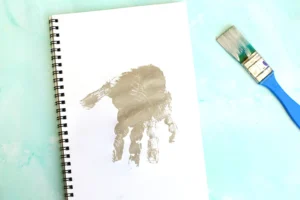 a notebook with a gray handprint in paint for this e is for elephant handprint craft
