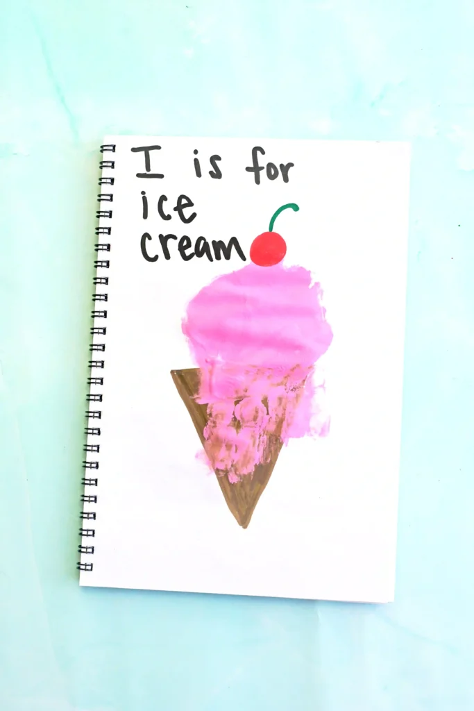 a letter I handprint craft that is an ice cream cone with a pink ice cream handprint, a cherry, and the words :I is for ice cream"