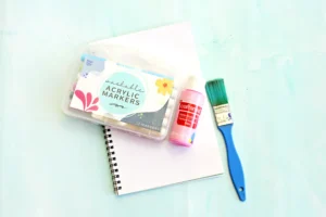 supplies for this alphabet craft for kids: paper, pink paint, markers, and a paintbrush