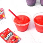 a Kool-Aid Slushie in a clear cup with a red straw