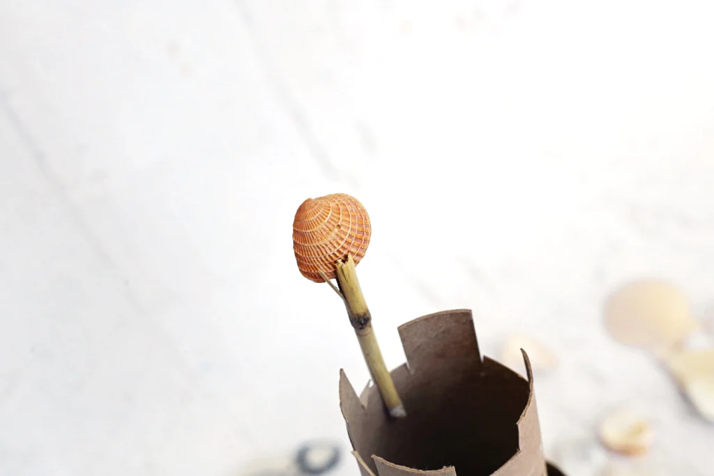 a small twig with a seashell glued on top