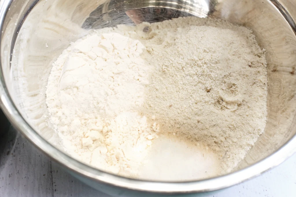 Metal mixing bowl with white flour on the left and sand on the right.