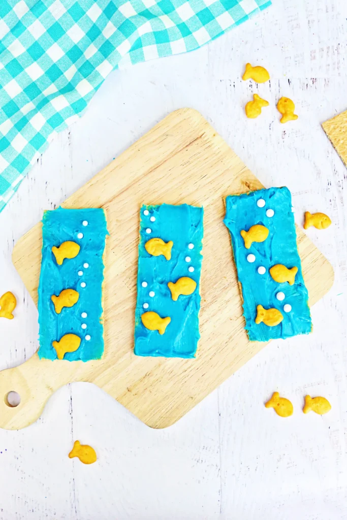Ocean Graham Crackers - Cultivating Brilliant Minds Ocean Graham Crackers that are graham crackers with blue frosting, goldfish crackers, and csprinkles