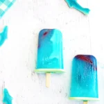 ocean popsicles made out of lemonade with gummy sharks inside for a summer party dessert, shark week dessert, or poolside snack