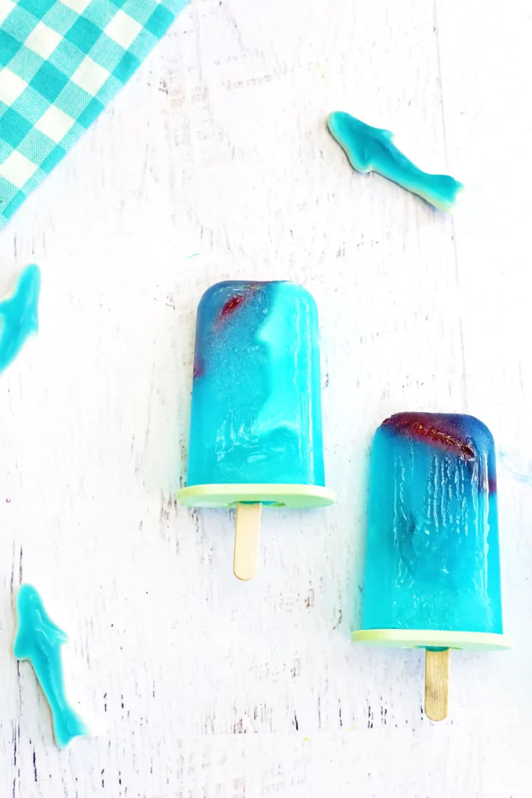 ocean popsicles made out of lemonade with gummy sharks inside for a summer party dessert, shark week dessert, or poolside snack