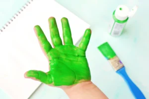 Child's hand covered in bright green paint for this f is for frog handprint craft