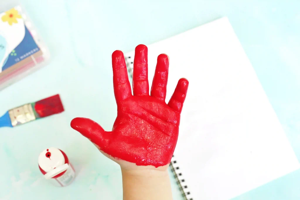 a child's hand painted red for this alphabet craft for kids