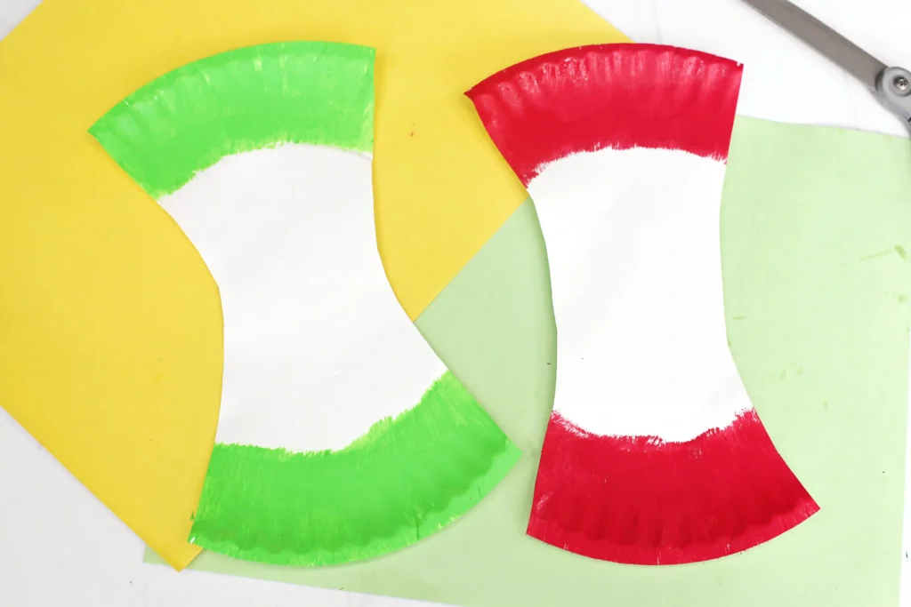 paper plates cut into the shape of an apple core and painted red and green to look like apples for this fall craft for kids