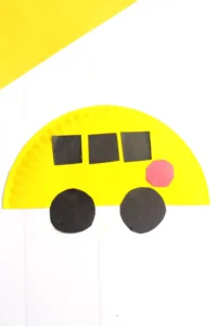 a paper plate school bus craft that is a paper plate cut in half, and painted yellow with construction paper windows, stop sign, and wheels