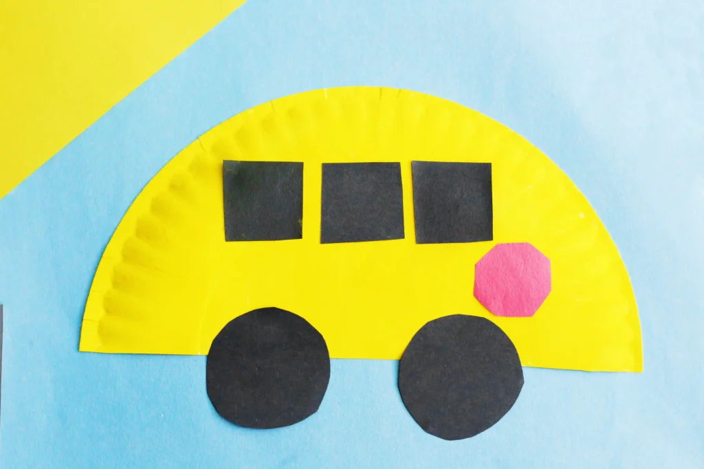 a paper plate schools bus craft that is a paper plate cut in half, and painted yellow with construction paper windows, stop sign, and wheels