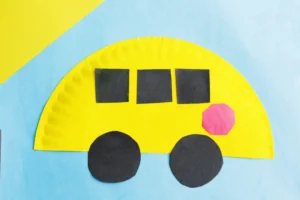 a paper plate school bus craft that is a paper plate cut in half, and painted yellow with construction paper windows, stop sign, and wheels