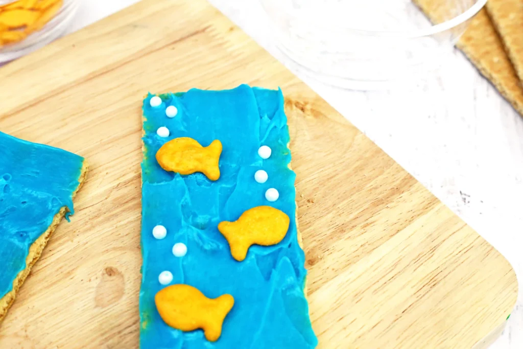 Ocean Graham Crackers - Cultivating Brilliant Minds Ocean Graham Crackers that are graham crackers with blue frosting, goldfish crackers, and sprinkles