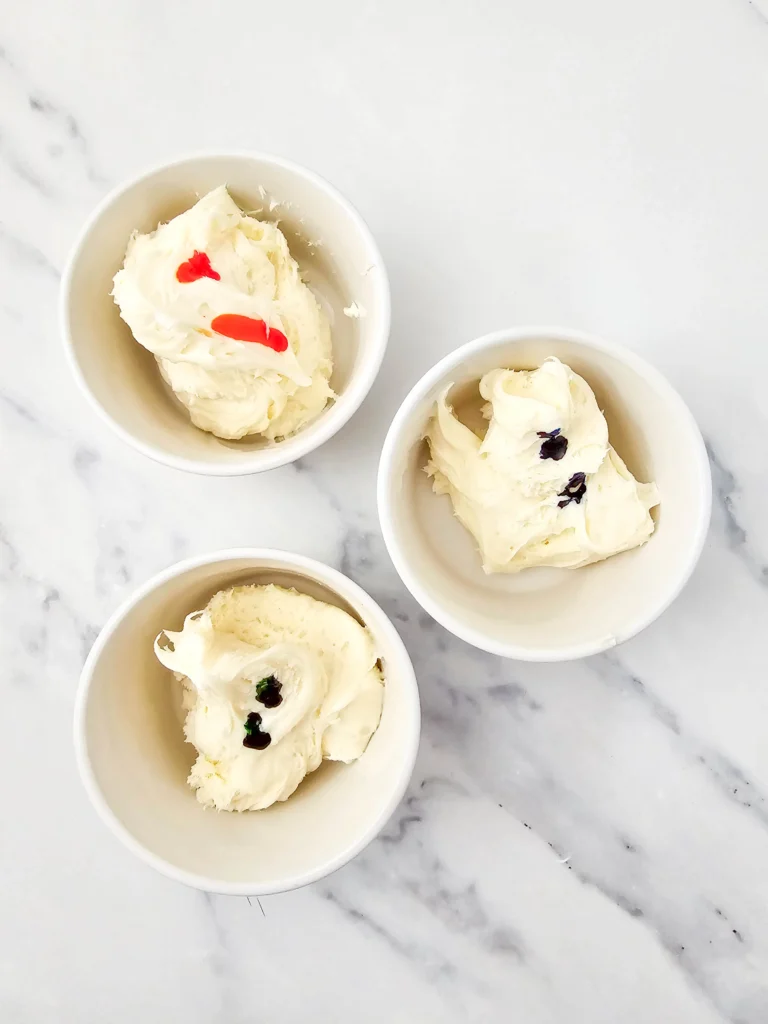 bowls of frosting with drops of food coloring in each for this lego dessert