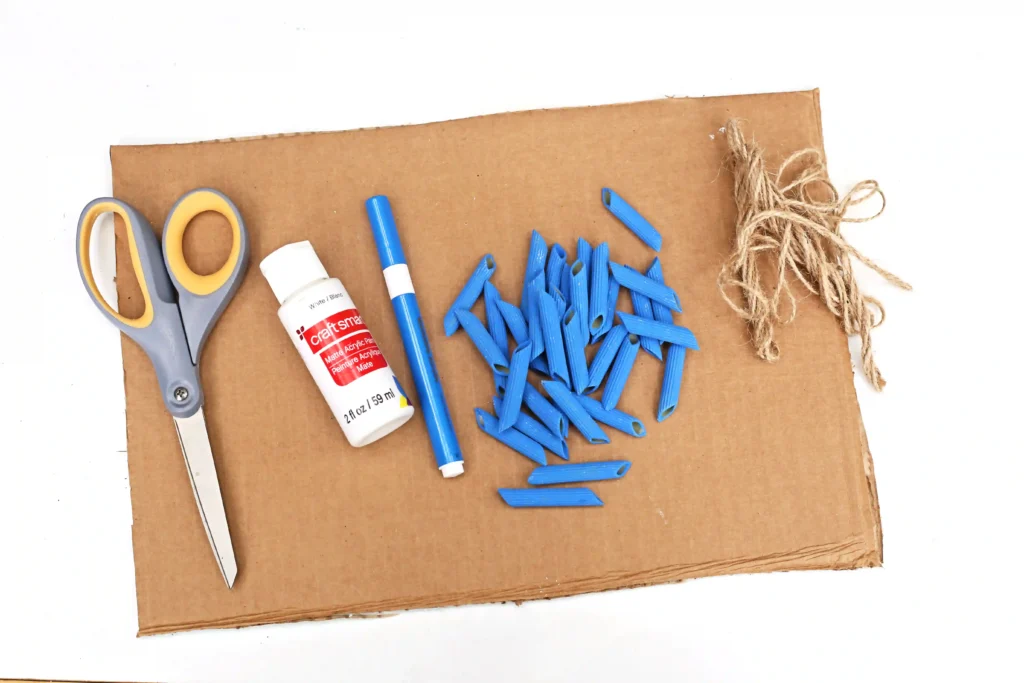 supplies for this preschool math activity- cardboard, scissors, white paint, blue marker, blue dyed pasta, and twine