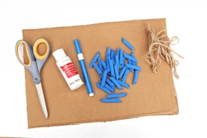 supplies for this preschool math activity- cardboard, scissors, white paint, blue marker, blue dyed pasta, and twine
