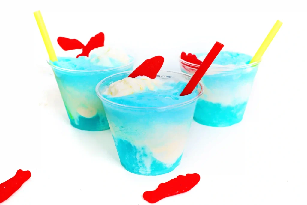 a seafoam ice cream float made with blue drink, vanilla ice cream and swedish fish for a poolside snack