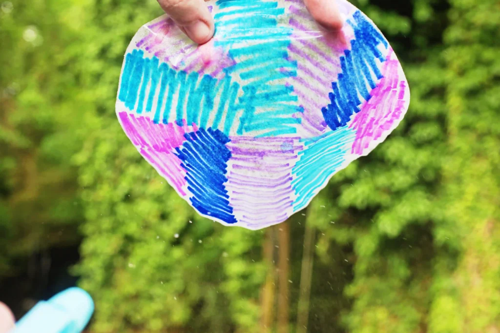 Coffee Filter Jellyfish Craft - Cultivating Brilliant Minds a person spraying a colored coffee filter with water for this coffee filter craft