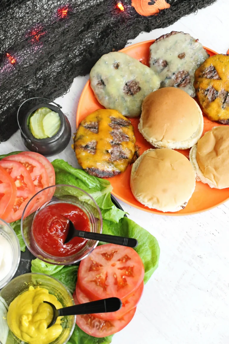 a halloween dinner idea with cheeseburgers that have ghost faces cut out of the cheese