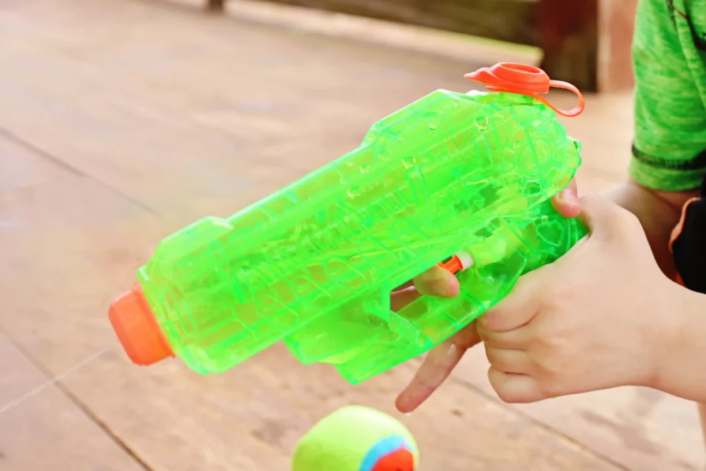 Outdoor Water Play Activity - Cultivating Brilliant Minds a kid holding a green squirt gun