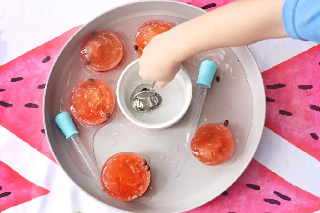 a kid using a measuring cup to scoop warm water out of a white bowl
