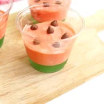 watermelon pudding cups with green jello and pink pudding with chocolate chips on top