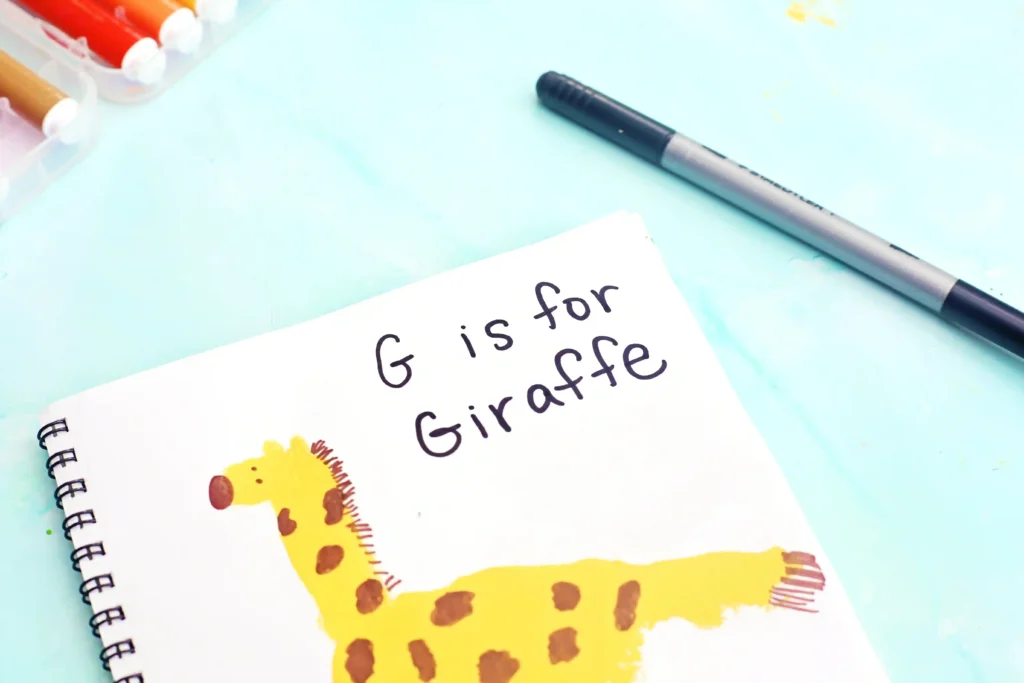 a letter g handprint craft that is a yellow handprint decorated to look like a giraffe with words "G is for giraffe"