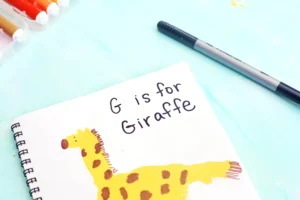 a letter g handprint craft that is a yellow handprint decorated to look like a giraffe with words "G is for giraffe"