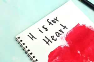 a notebook with a handprint heart that reads "H is for heart"