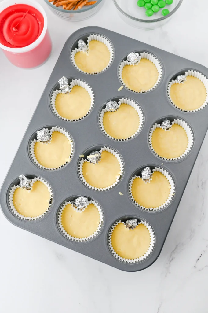 Apple Cupcakes - Cultivating Brilliant Minds Unbaked cupcakes in a muffin tin with foil toppers, ready to bake on a kitchen counter for these back to school cupcakes