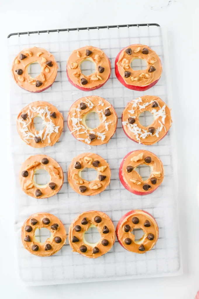 Apple Slice Cookies with peanut butter, chocolate chips, and coconut flakes on a cooling rack