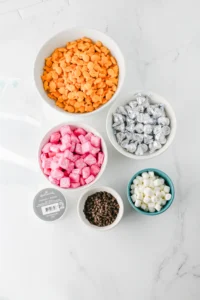 ingredients for these back to school gifts - chocolate chips, marshmallows, goldfish, pink starburst, hershey kisses, piping bags, and string