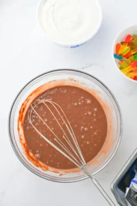 Top-down view of a glass mixing bowl filled with chocolate pudding and a whisk, for this classroom snack