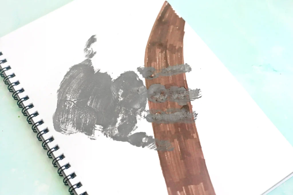 White notebook page with a brown branch drawn on and a gray handprint for this k is for koala handprint craft