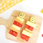 lego fruit skewers that look like lego people with watermelon, pineapple, and cantaloupe