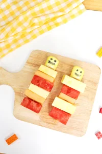 lego fruit skewers that look like lego people with watermelon, pineapple, and cantaloupe