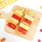 lego fruit skewers that look like lego people with watermelon, pineapple, and cantaloupe