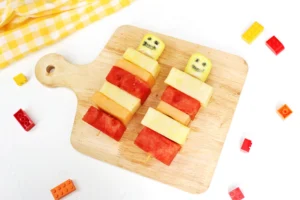 lego fruit skewers that look like lego people with watermelon, pineapple, and cantaloupe