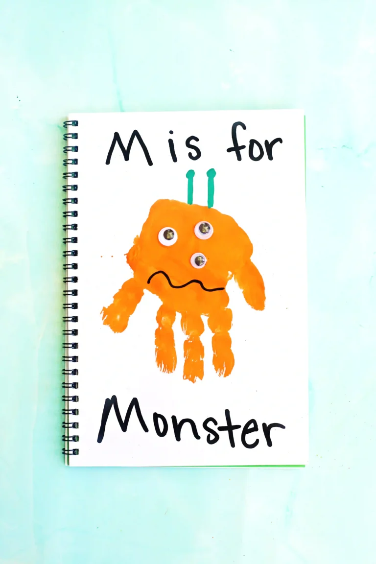 a letter m handprint craft that is an orange handprint decorated to look like a monster with the words "M is for monster" written on the page