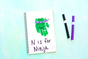 a letter n handprint craft that is a green handprint decorated to look like a ninja