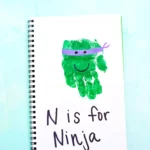 a letter n handprint craft that is a green handprint decorated to look like a ninja