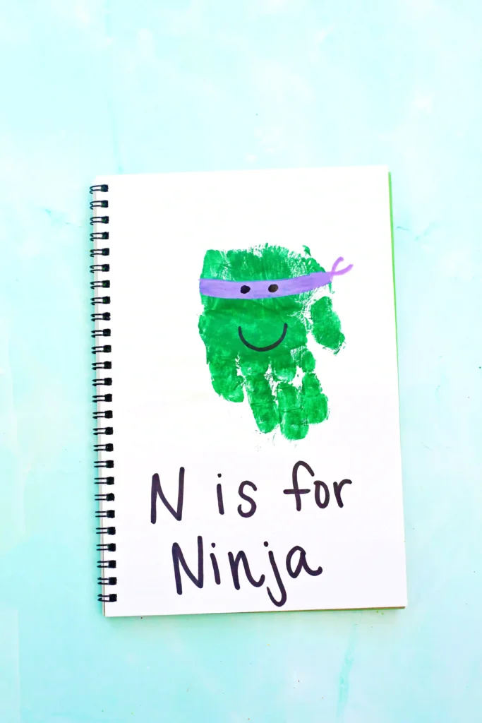 a letter n handprint craft that is a green handprint decorated to look like a ninja