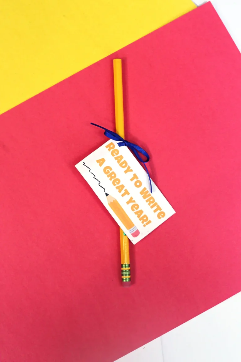 Yellow pencil with a tag that reads 'Ready to write a great year,' resting on a pink and yellow diagonal background.