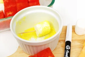 Ramekin with yellow sanding sugar with a marshmallow being rolled in it