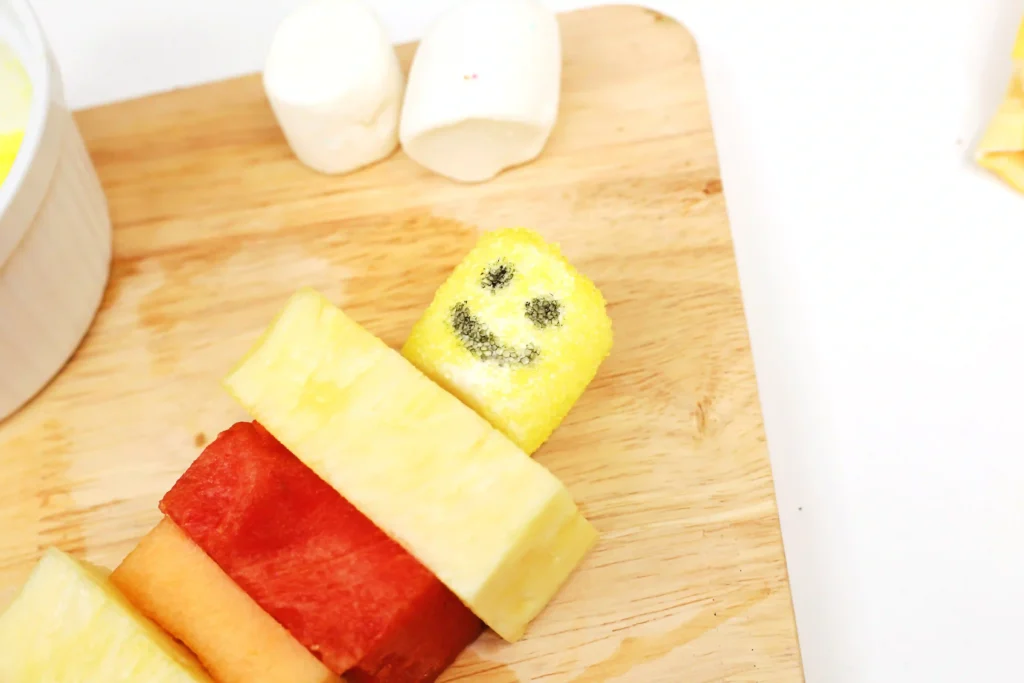 lego fruit skewers that look like lego people with watermelon, pineapple, and cantaloupe