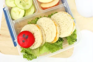 a Very Hungry Caterpillar Lunch Box Idea that us sandwiches and babybel cheese on a bed of lettuce to look like a caterpillar
