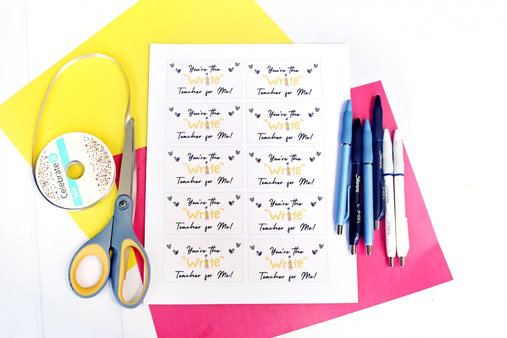 back to school printable tags for teachers: a Sheet of small cards with the text'You're the Write Teacher for Me!' surrounded by craft supplies like scissors, tape, and colored papers in a bright workspace.