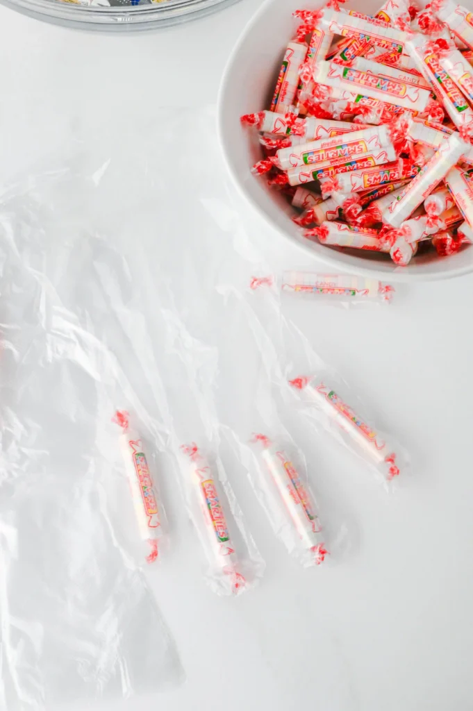Halloween Treat Bags - Cultivating Brilliant Minds a clear glove with smarties candies inside next to a bowl filled with smarties