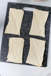 Two elongated sheets of pale dough laid side by side on a dark speckled cutting board, ready to bake.