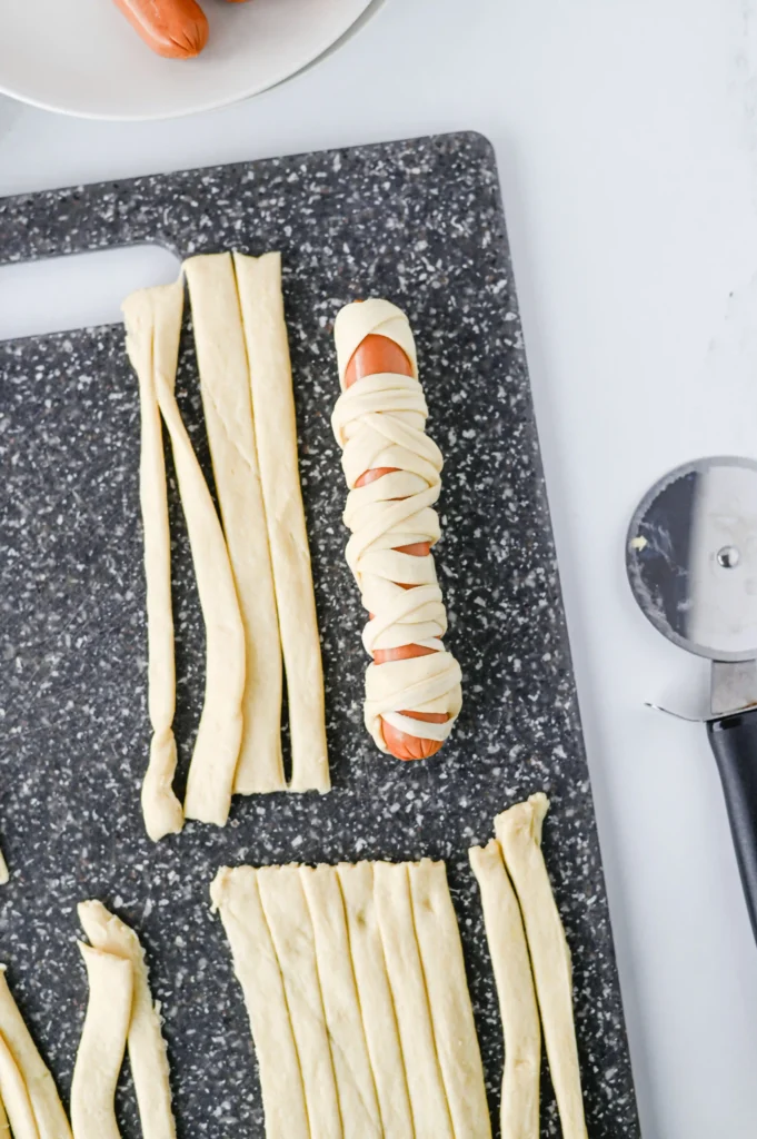 Mummy Hot Dogs - Cultivating Brilliant Minds a hot dog wrapped with pastry dough to look like a mummy