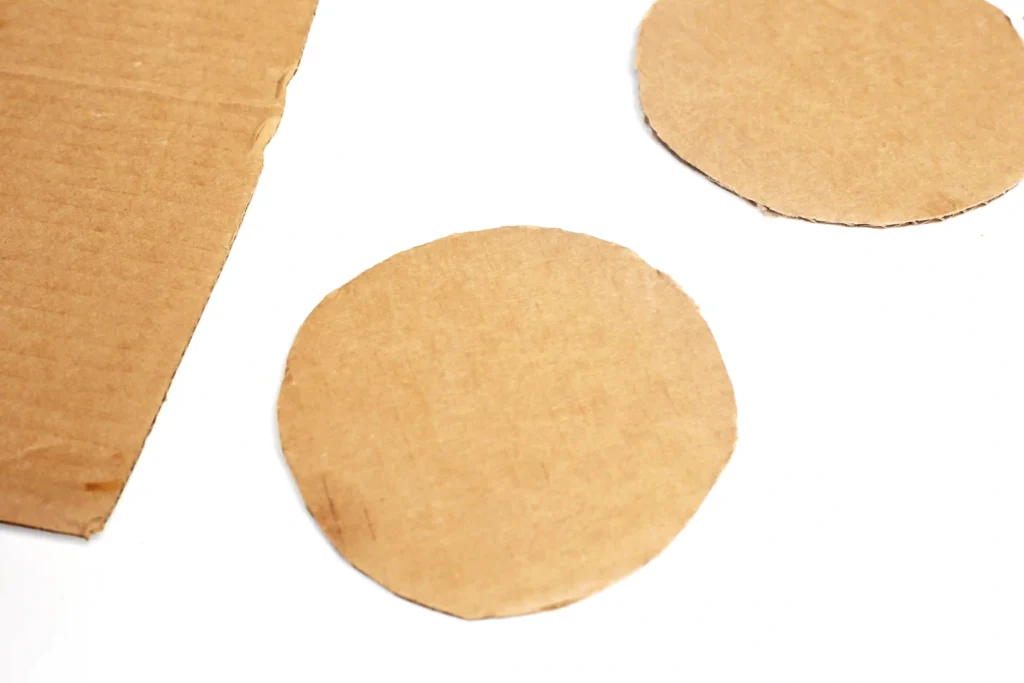 Several round pieces of brown cardboard torn from a sheet, scattered on a white background.